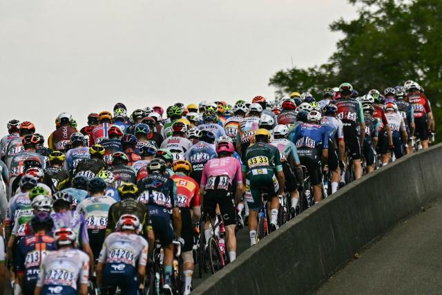 The pack of riders (peloton) cycles at the start of the 14th stage of the 113th edition of the Tour de France cycling race, 155,3 km between Mulhouse and Le Markstein in the Vosges mountains, on July 18, 2026. (Photo by Loic VENANCE / AFP)