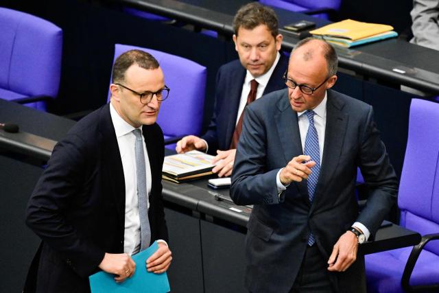 (FILES) German Chancellor Friedrich Merz (R) gestures next to Parliamentary group leader of Germany's Christian Democratic Union (CDU) Jens Spahn (L) while German Finance Minister and Vice Chancellor Lars Klingbeil (C back) looks on during a session of the German Bundestag (lower house of parliament) on June 11, 2026, ahead of an EU summit. Jens Spahn, a prominent figure in German Chancellor Friedrich Merz's centre-right party resigned his leadership post on July 18, 2026, party sources told AFP, amid controversy over his use of a surrogate mother in the US despite a ban on the practice in Germany. "In recent days, I have come to realise that my personal happiness in starting a family with my husband and becoming a father is incompatible with my political office," Jens Spahn, the chairman of the CDU's faction in parliament, wrote in a letter to colleagues that was obtained by AFP. (Photo by John MACDOUGALL / AFP)