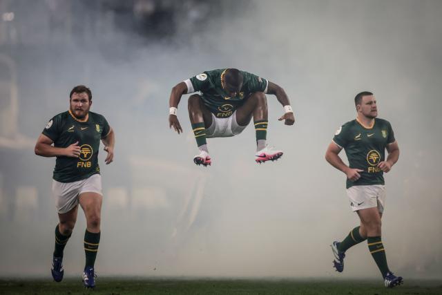 TOPSHOT - South Africa's fullback Aphelele Fassi (C) jumps as he takes to the pitch alongside South Africa's hooker Jan-Hendrik Wessels (L) and hooker Andre-Hugo Venter (R) during the rugby Nations Championship match between South Africa and Wales at Kings Park Stadium in Durban on July 18, 2026. (Photo by PHILL MAGAKOE / AFP)