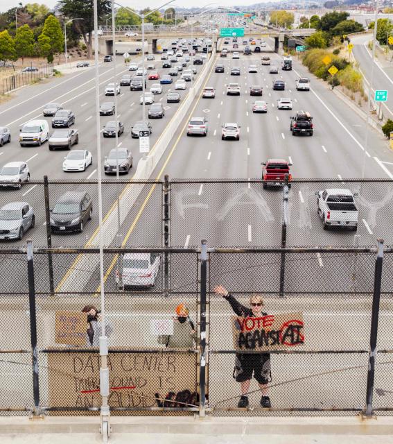 People hold up signs on a pedestrian bridge during a nationwide protest against AI data center expansion in Berkeley, California on July 18, 2026. (Photo by Josh Edelson / AFP)