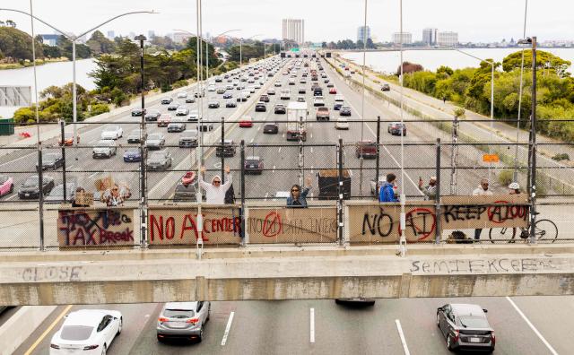 People hold up signs on a pedestrian bridge during a nationwide protest against AI data center expansion in Berkeley, California on July 18, 2026. (Photo by Josh Edelson / AFP)