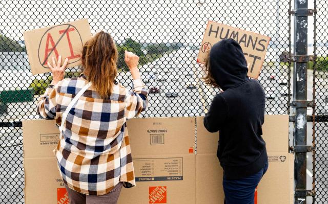 People hold up signs on a pedestrian bridge during a nationwide protest against AI data center expansion in Berkeley, California on July 18, 2026. (Photo by Josh Edelson / AFP)
