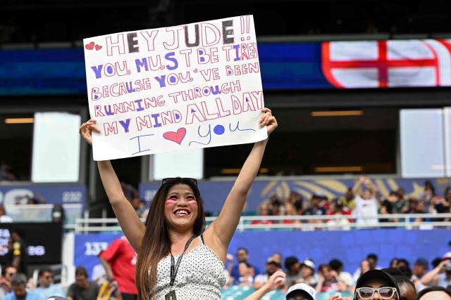 A football fan shows a sign with a message to England's midfielder Jude Bellingham ahead of the 2026 World Cup football tournament third-place match between France and England at the Miami Stadium in Miami on July 18, 2026.  (Photo by ROBERTO SCHMIDT / AFP)