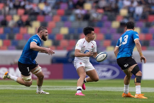 England's fly-half Marcus Smith runs with the ball past Argentina's flanker Marcos Kremer (L) and centre Matias Moroni during the Rugby Union Nations Championship match between Argentina and England at Unico Madre de Ciudades stadium in Santiago del Estero, Argentina, on July 18, 2026. Argentina players wear a blue jersey as a tribute to the Argentina national football team that defeated England with goals by Diego Maradona at the Mexico 1986 World Cup. (Photo by Juan GASPARINI / AFP)