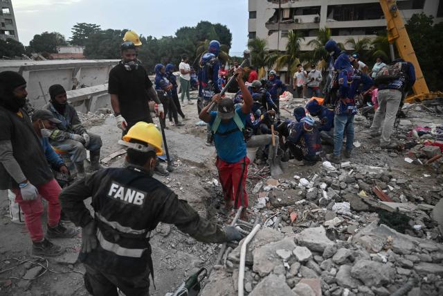 Volunteers and rescuers search for bodies amid debris of buildings damaged by the June 24 earthquakes, in Tanaguarena, state of La Guaira; Venezuela, on July 18, 2026. The twin earthquakes that struck Venezuela last month killed over 5,000 people, officials said, while announcing they drew hundreds of millions of dollars from the International Monetary Fund (IMF) for reconstruction. (Photo by Juan BARRETO / AFP)