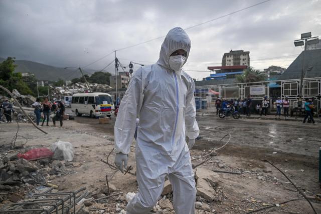 A forensic walks amid rubble of buildings damaged by the June 24 earthquakes, in Tanaguarena, state of La Guaira; Venezuela, on July 18, 2026. The twin earthquakes that struck Venezuela last month killed over 5,000 people, officials said, while announcing they drew hundreds of millions of dollars from the International Monetary Fund (IMF) for reconstruction. (Photo by Juan BARRETO / AFP)