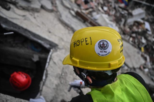 Volunteers and Mexican rescuers search for bodies amid debris of buildings damaged by the June 24 earthquakes, in Tanaguarena, state of La Guaira; Venezuela, on July 18, 2026. The twin earthquakes that struck Venezuela last month killed over 5,000 people, officials said, while announcing they drew hundreds of millions of dollars from the International Monetary Fund (IMF) for reconstruction. (Photo by Juan BARRETO / AFP)