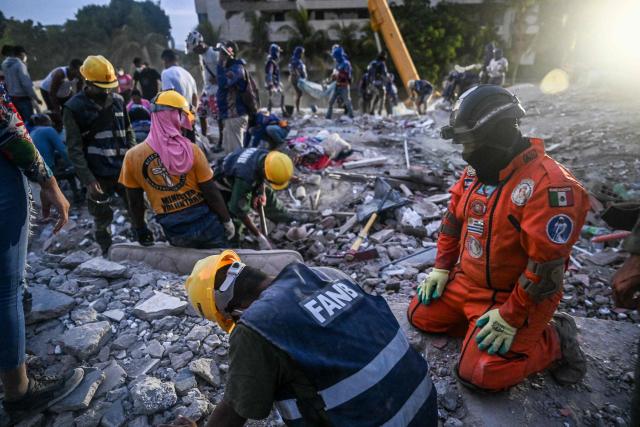 Volunteers and Mexican rescuers search for bodies amid debris of buildings damaged by the June 24 earthquakes, in Tanaguarena, state of La Guaira; Venezuela, on July 18, 2026. The twin earthquakes that struck Venezuela last month killed over 5,000 people, officials said, while announcing they drew hundreds of millions of dollars from the International Monetary Fund (IMF) for reconstruction. (Photo by Juan BARRETO / AFP)