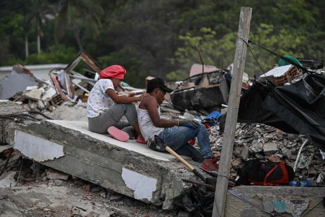 A couple rests amid debris of buildings damaged by the June 24 earthquakes, in Tanaguarena, state of La Guaira; Venezuela, on July 18, 2026. The twin earthquakes that struck Venezuela last month killed over 5,000 people, officials said, while announcing they drew hundreds of millions of dollars from the International Monetary Fund (IMF) for reconstruction. (Photo by Juan BARRETO / AFP)