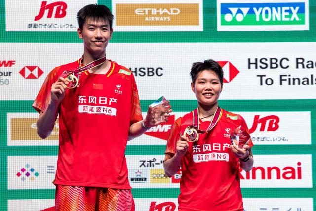 Gold medalists China’s Feng Yanzhe and Huang Dongping celebrate on the podium after their victory against Hong Kong's Tang Chun Man and Tse Ying Suet in their mixed doubles final match of the Japan Open badminton tournament at Tokyo Gymnasium in Tokyo on July 19, 2026. (Photo by Yuichi YAMAZAKI / AFP)