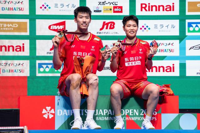 Gold medalists China’s Feng Yanzhe and Huang Dongping pose on the podium after their victory against Hong Kong's Tang Chun Man and Tse Ying Suet in their mixed doubles final match of the Japan Open badminton tournament at Tokyo Gymnasium in Tokyo on July 19, 2026. (Photo by Yuichi YAMAZAKI / AFP)
