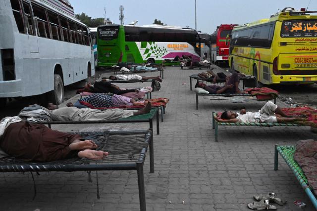 Bus drivers sleep at a station amid a heatwave in Lahore in the early hours of July 19, 2026. (Photo by Arif ALI / AFP)