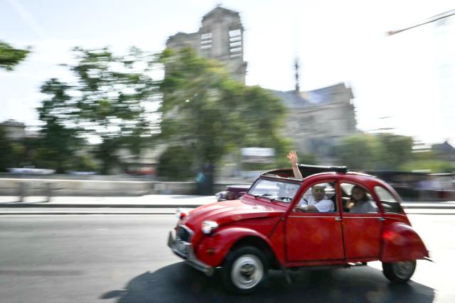 A participant drives his vintage Citroen 2CV past Notre-Dame de Paris cathedral during the 19th Summer parade of vintage vehicles in Paris on July 19, 2026. (Photo by Lou BENOIST / AFP)