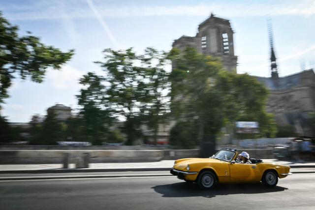 A participant drives his vintage car past Notre-Dame de Paris cathedral during the 19th Summer parade of vintage vehicles in Paris on July 19, 2026. (Photo by Lou BENOIST / AFP)