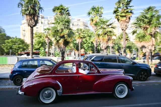 A participant drives his vintage car during the 19th Summer parade of vintage vehicles in Paris on July 19, 2026. (Photo by Lou BENOIST / AFP)