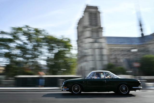 A participant drives his vintage car past Notre-Dame de Paris cathedral during the 19th Summer parade of vintage vehicles in Paris on July 19, 2026. (Photo by Lou BENOIST / AFP)