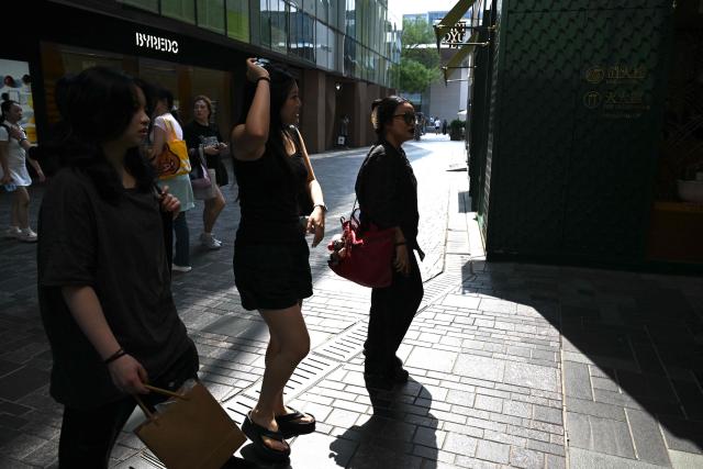 People walk through a shopping mall in Beijing on July 19, 2026. (Photo by GREG BAKER / AFP)