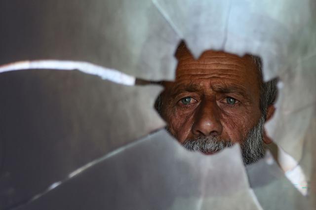 A Palestinian man checks a broken window at the damaged Al-Taqwa mosque, whose entrance was torched and walls were daubed with Hebrew graffiti in an attack allegedly carried out by Israeli settlers in the Palestinian village of Al-Tuwani, south of Yatta, near Hebron in the occupied West Bank on July 19, 2026. (Photo by HAZEM BADER / AFP)