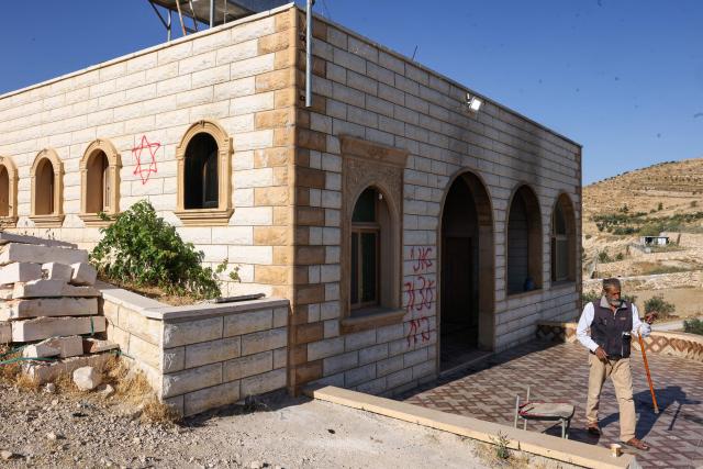A Palestinian man checks the damaged Al-Taqwa mosque, whose entrance was torched and walls were daubed with Hebrew graffiti in an attack allegedly carried out by Israeli settlers in the Palestinian village of Al-Tuwani, south of Yatta, near Hebron in the occupied West Bank on July 19, 2026. (Photo by HAZEM BADER / AFP)