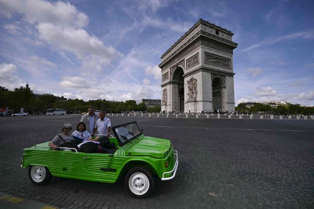 Participants pose with their Citroen Mehari next to the Arc de Triomphe during the 19th Summer parade of vintage vehicles in Paris on July 19, 2026. (Photo by LOU BENOIST / AFP)
