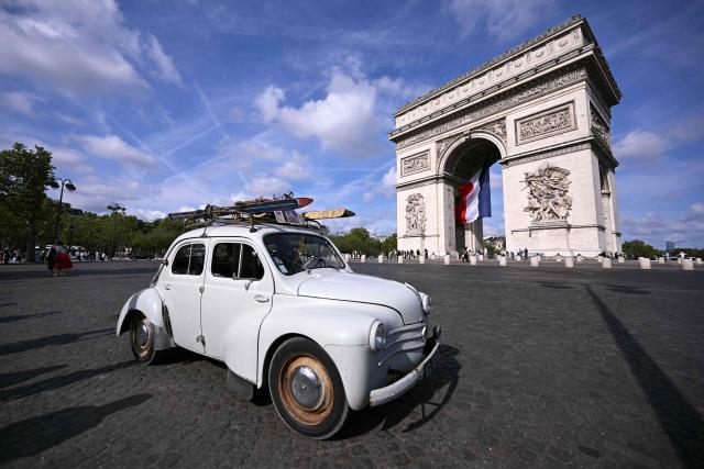 A participant drives his vintage Renault 4CV past the Arc de Triomphe during the 19th Summer parade of vintage vehicles in Paris on July 19, 2026. (Photo by LOU BENOIST / AFP)