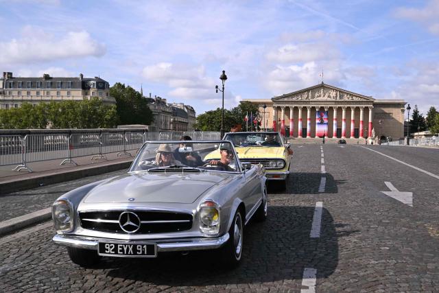 A participant drives his Mercedes Beenz 280 SL past the National Assembly during the 19th Summer parade of vintage vehicles in Paris on July 19, 2026. (Photo by LOU BENOIST / AFP)