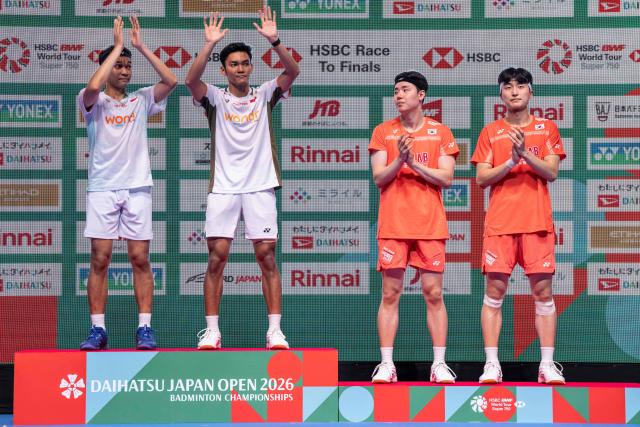 Gold medallists Indonesia’s Fajar Alfian and Muhammad Shohibul Fikri (L) celebrate on the podium after their victory against South Koreaґs Kim Won-ho and Seo Seung-jae in their men's doubles final match of the Japan Open badminton tournament at Tokyo Gymnasium in Tokyo on July 19, 2026. (Photo by Yuichi YAMAZAKI / AFP)