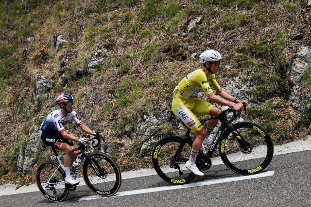 Red Bull - BORA - hansgrohe team's Australian rider Jai Hindley (L) and UAE Team Emirates - XRG's Slovenian rider Tadej Pogacar wearing the overall leader's yellow jersey cycle during the 15th stage of the 113th edition of the Tour de France cycling race, 183,9 km between Champagnole and Plateau de Solaison in the Jura mountains, on July 19, 2026. (Photo by Anne-Christine POUJOULAT / AFP)