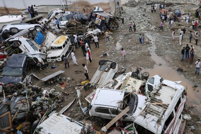 Residents look at damaged vehicles after flash flood and landslide triggered by heavy rains wreaked havoc at Rajouri district in India's Jammu region on July 19, 2026. Flash floods and landslides caused by monsoon rains killed at least 19 people in India on July 19, officials and local media said, as authorities mounted rescue operations in affected regions. (Photo by Mir Imran / AFP) / ALTERNATIVE CROP