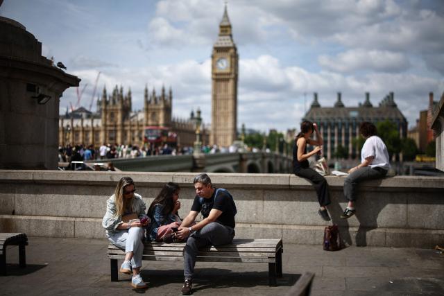 People sit out on the south side of the River Thames with a view of Elizabeth Tower (back C), commonly referred to as "Big Ben", on the north side in Westminster in central London on July 19, 2026, a day ahead of when Prime Minister Keir Starmer steps down and Andy Burnham becomes the next British leader. Little known on the international stage, Andy Burnham is expected to broadly maintain Keir Starmer's position on major foreign policy issues as the UK's next prime minister on July 20. (Photo by Henry Nicholls / AFP)