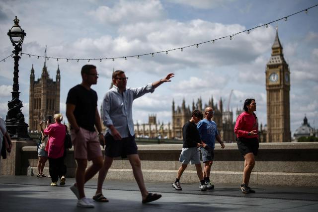 People walk along the south side of the River Thames with a view of Elizabeth Tower (back R), commonly referred to as "Big Ben", and the Palace of Westminster (back L) on the north side in Westminster in central London on July 19, 2026, a day ahead of when Prime Minister Keir Starmer steps down and Andy Burnham becomes the next British leader. Little known on the international stage, Andy Burnham is expected to broadly maintain Keir Starmer's position on major foreign policy issues as the UK's next prime minister on July 20. (Photo by Henry Nicholls / AFP)