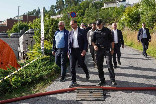 Crown Prince Haakon of Norway inspects the fire site with emergency services and representatives from the municipality's crisis management at the scene of the accident by Krokstadelva in Drammen, south-west of Oslo, Norway, on July 19, 2026, two days after a large fire has spread from terraced houses. (Photo by Thomas Fure / NTB / AFP) / Norway OUT