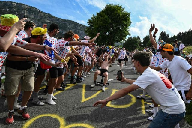 A spectator wielding a chainsaw rides a desk chair downhill as crowds await the pack of riders (peloton) in the final ascent of the 15th stage of the 113th edition of the Tour de France cycling race, 183,9 km between Champagnole and Plateau de Solaison in the Jura mountains, on July 19, 2026. (Photo by Jeff PACHOUD / AFP)