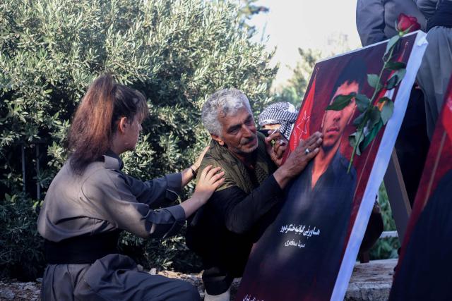 Members of the Iranian Kurdish opposition Komala party mourn during the funeral of nine Peshmerga fighters at the Sheikh Ahmed Hindi cemetery in the city of Sulaymaniyah, in the autonomous Kurdistan region in northern Iraq on July 19, 2026. Drone and rocket strikes killed nine members of an Iranian Kurdish armed opposition group in Iraq's Kurdistan region on July 17, the exiled party said, blaming the attack on Iran. The attacks, which the Kurdish government also blamed on Tehran, come against the backdrop of renewed military escalation between the United States and Iran, Iraq's main allies. (Photo by Shwan MOHAMMED / AFP) / 