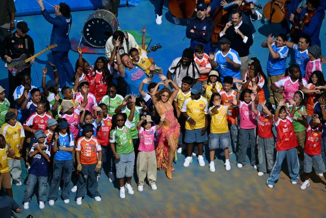 Colombian singer, songwriter and producer Shakira (C), Nigerian singer, songwriter, and record producer Burna Boy and US actor Jason Sudeikis gesture with performers at the Half Time Show during the 2026 World Cup football tournament final match between Spain and Argentina at the New York/New Jersey Stadium in East Rutherford on July 19, 2026.  (Photo by MAURO PIMENTEL / AFP)