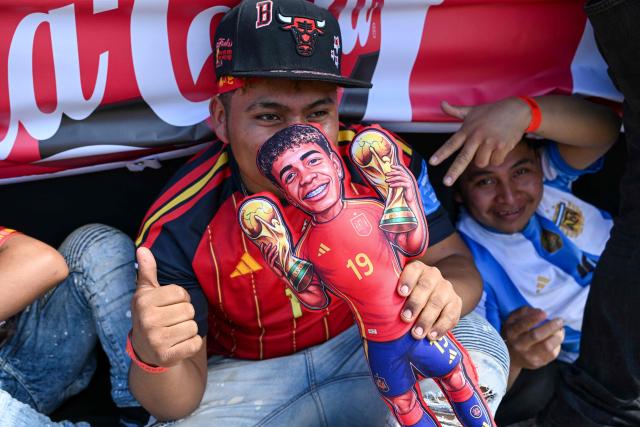 A man wearing a Spain jersey holds a Lamine Yamal doll while watching the FIFA World Cup final football match between Spain and Argentina on a giant screen in Guatemala City on July 19, 2026. (Photo by Johan ORDONEZ / AFP)