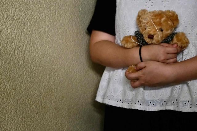 This photo taken in Hong Kong on June 16, 2026 shows Bobo holding a teddy bear, a woman who suffered persistent child sexual abuse for several years, after speaking on the condition of anonymity about her childhood experience. Hong Kong has sought to overhaul its decades-old sexual offence laws, opening sweeping reforms to public consultation this month. The long-awaited reforms will introduce stricter penalties for sexual crimes, but survivors say the changes still do not bar the defence of "mistaken belief". (Photo by Tommy WANG / AFP) / To go with AFP story Hong Kong-China-crime-law-women-children, FOCUS by Tommy WANG