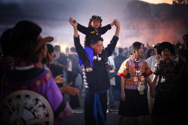 A man carries a child on his shoulders as they celebrate the Torch Festival, held by the Yi ethnic minority, in Puge County, Liangshan Prefecture, in China’s southwest Sichuan Province on July 19, 2026. The celebrations took in traditional folk activities such as horse racing, bullfighting, and dancing and singing around bonfires. (Photo by CN-STR / AFP) / China OUT