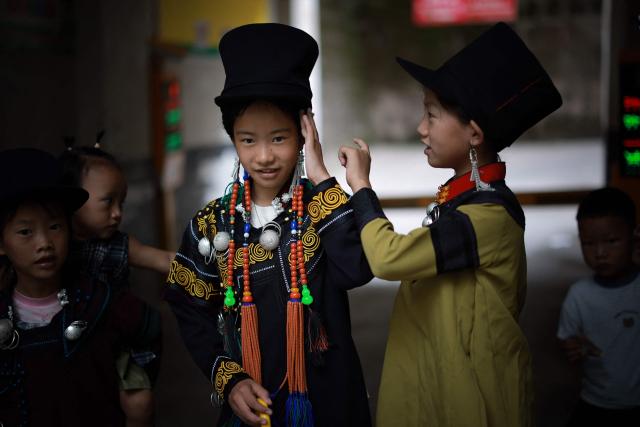 Children get dressed up as they prepare to celebrate the Torch Festival, held by the Yi ethnic minority, in Puge County, Liangshan Prefecture, in China’s southwest Sichuan Province on July 19, 2026. The celebrations took in traditional folk activities such as horse racing, bullfighting, and dancing and singing around bonfires. (Photo by CN-STR / AFP) / China OUT