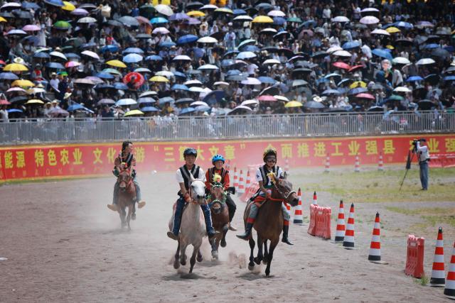 Young boys race horses in front of a crowd as they celebrate the Torch Festival, held by the Yi ethnic minority, in Puge County, Liangshan Prefecture, in China’s southwest Sichuan Province on July 19, 2026. The celebrations took in traditional folk activities such as horse racing, bullfighting, and dancing and singing around bonfires. (Photo by CN-STR / AFP) / China OUT