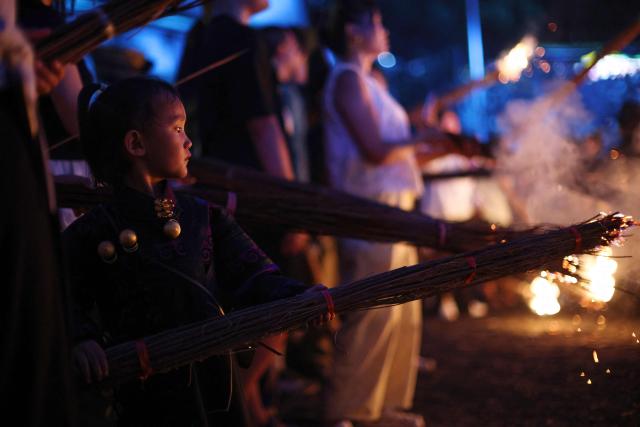A child holds a burning torch during celebrations of the Torch Festival, held by the Yi ethnic minority, in Puge County, Liangshan Prefecture, in China’s southwest Sichuan Province on July 19, 2026. The celebrations took in traditional folk activities such as horse racing, bullfighting, and dancing and singing around bonfires. (Photo by CN-STR / AFP) / China OUT