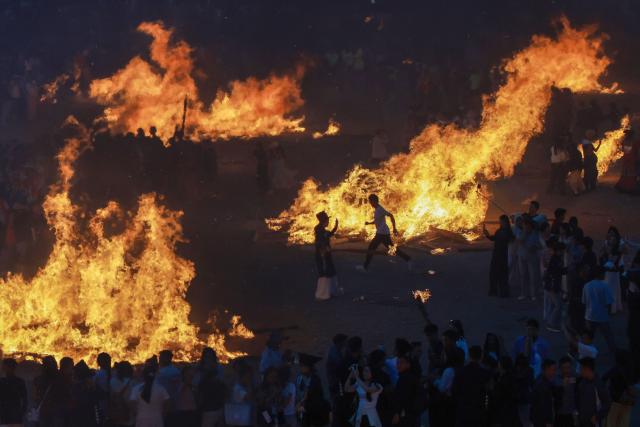 People gather around bonfires as they celebrate the Torch Festival, held by the Yi ethnic minority, in Puge County, Liangshan Prefecture, in China’s southwest Sichuan Province on July 19, 2026. The celebrations took in traditional folk activities such as horse racing, bullfighting, and dancing and singing around bonfires. (Photo by CN-STR / AFP) / China OUT