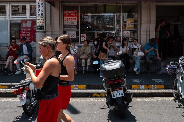 People sit on a bench in the shadow while visiting Tsukiji outer market in Tokyo on July 20, 2026, as temperatures reach 36°C in Japan's capital. (Photo by Philip FONG / AFP)