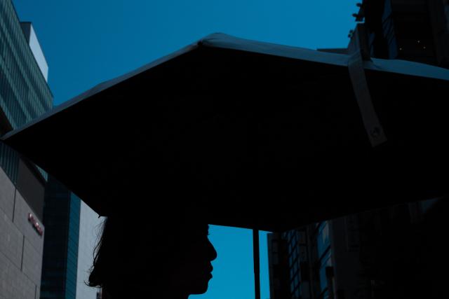 A woman walks with an umbrella while visiting Ginza district in Tokyo on July 20, 2026, as temperatures reach 36°C in Japan's capital. (Photo by Philip FONG / AFP)