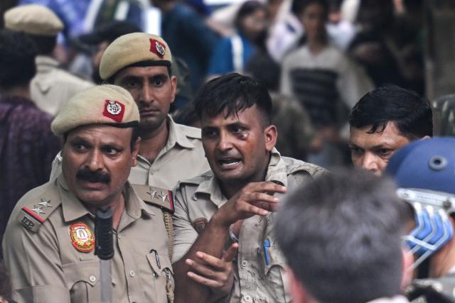 Police personnel help an injured fellow policeman after a clash with the supporters of the Cockroach Janta Party (CJP) during a protest demanding the resignation of India's Education Minister Dharmendra Pradhan over alleged NEET exam irregularities in New Delhi on July 20, 2026. Indian police fired tear gas and baton-charged protesters in New Delhi on July 20 as they tried to march on parliament to demand the resignation of the education minister over irregularities in major examinations. (Photo by Arun SANKAR / AFP)
