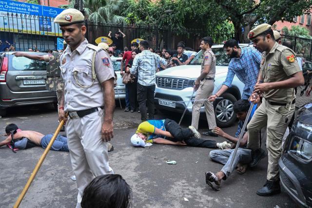 Supporters of the Cockroach Janta Party (CJP) lie on the road after clashing with police during a protest demanding the resignation of India's Education Minister Dharmendra Pradhan over alleged NEET exam irregularities in New Delhi on July 20, 2026. Indian police fired tear gas and baton-charged protesters in New Delhi on July 20 as they tried to march on parliament to demand the resignation of the education minister over irregularities in major examinations. (Photo by Arun SANKAR / AFP)