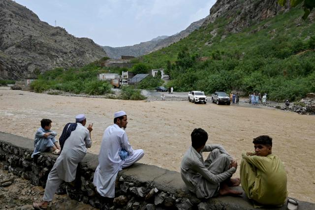 Commuters wait as floodwater swamps a road following heavy monsoon rains at Landi Kotal, in Pakistan's Khyber Pakhtunkhwa province on July 20, 2026. (Photo by Abdul MAJEED / AFP)
