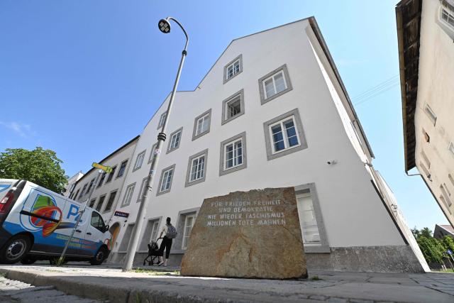 A memorial stone reading "For Peace, Freedom and Democracy - Never Again Fascism - Millions of Dead Warn" stands in front of the birth house of former German dictator Adolf Hitler that is turned into a police station, in Braunau am Inn, Austria on July 16, 2026. The controversial redesign of the house in the northern Austrian town of Braunau started in 2023. Following years of legal wrangling, the government took control of the dilapidated building in 2016 and decided to turn the house, where Hitler was born in 1889, into a police station that will be inaugurated on July 22, 2026. (Photo by KERSTIN JOENSSON / AFP)