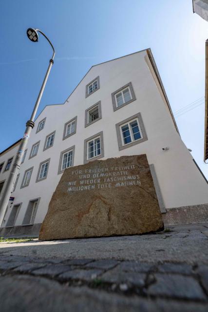 A memorial stone reading "For Peace, Freedom and Democracy - Never Again Fascism - Millions of Dead Warn" stands in front of the birth house of former German dictator Adolf Hitler that is turned into a police station, in Braunau am Inn, Austria on July 16, 2026. The controversial redesign of the house in the northern Austrian town of Braunau started in 2023. Following years of legal wrangling, the government took control of the dilapidated building in 2016 and decided to turn the house, where Hitler was born in 1889, into a police station that will be inaugurated on July 22, 2026. (Photo by KERSTIN JOENSSON / AFP)