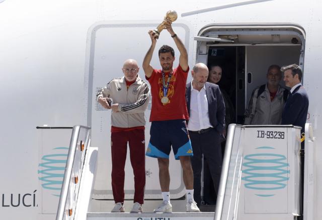 Spain's national football team's coach Luis de la Fuente (L), Spain's midfielder Rodri (C) and President of the Spanish Football Federation Rafael Louzan (3L) pose with their trophy upon their arrival from the US after winning the 2026 World Cup, in Madrid Barajas' airport, on July 20, 2026. Spain's World Cup winners come back home to a heroes' welcome in Madrid, where a million fans are expected to greet them after a night of raucous celebrations across the country. (Photo by Oscar DEL POZO / AFP)